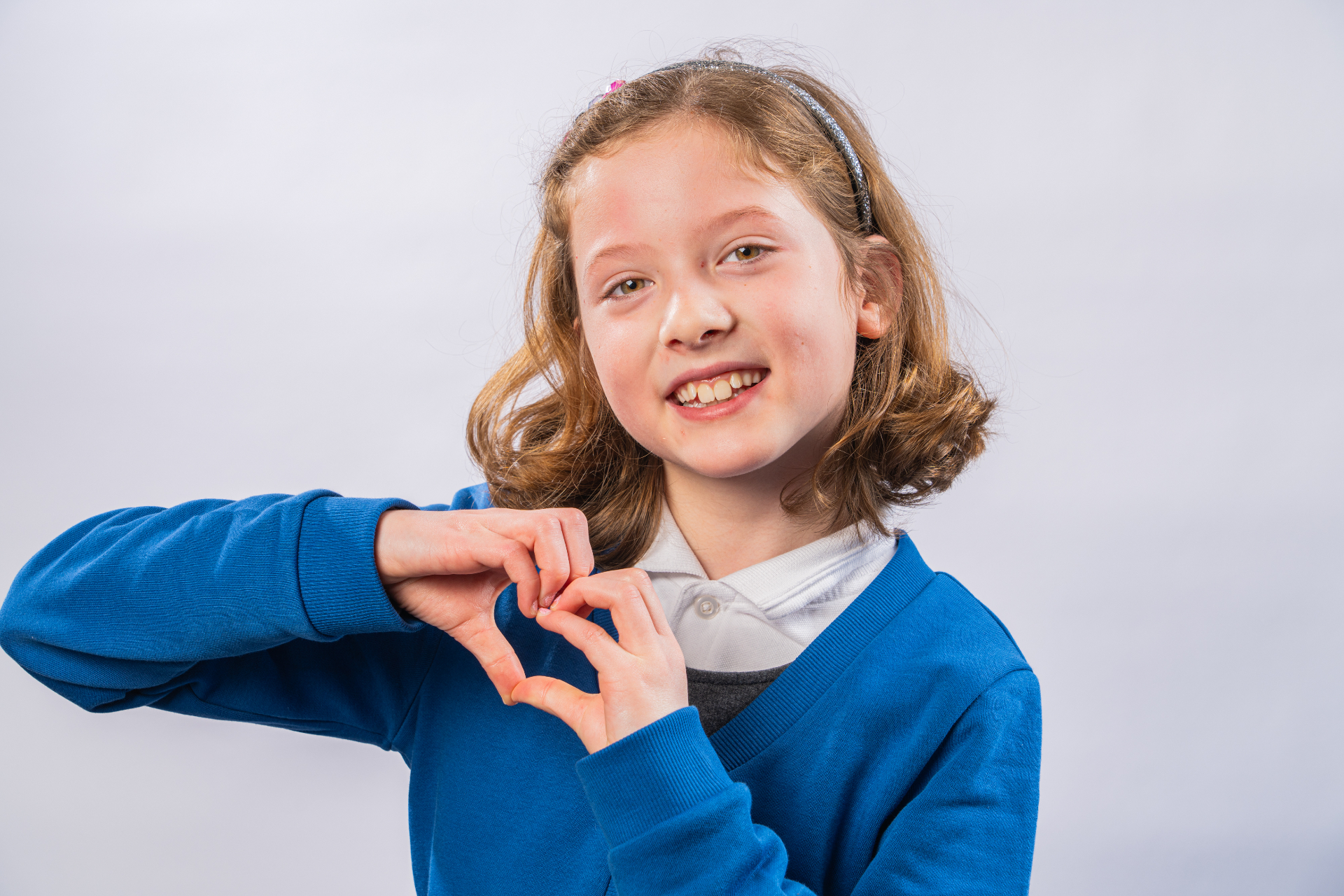Individual school portrait - girl making heart gesture