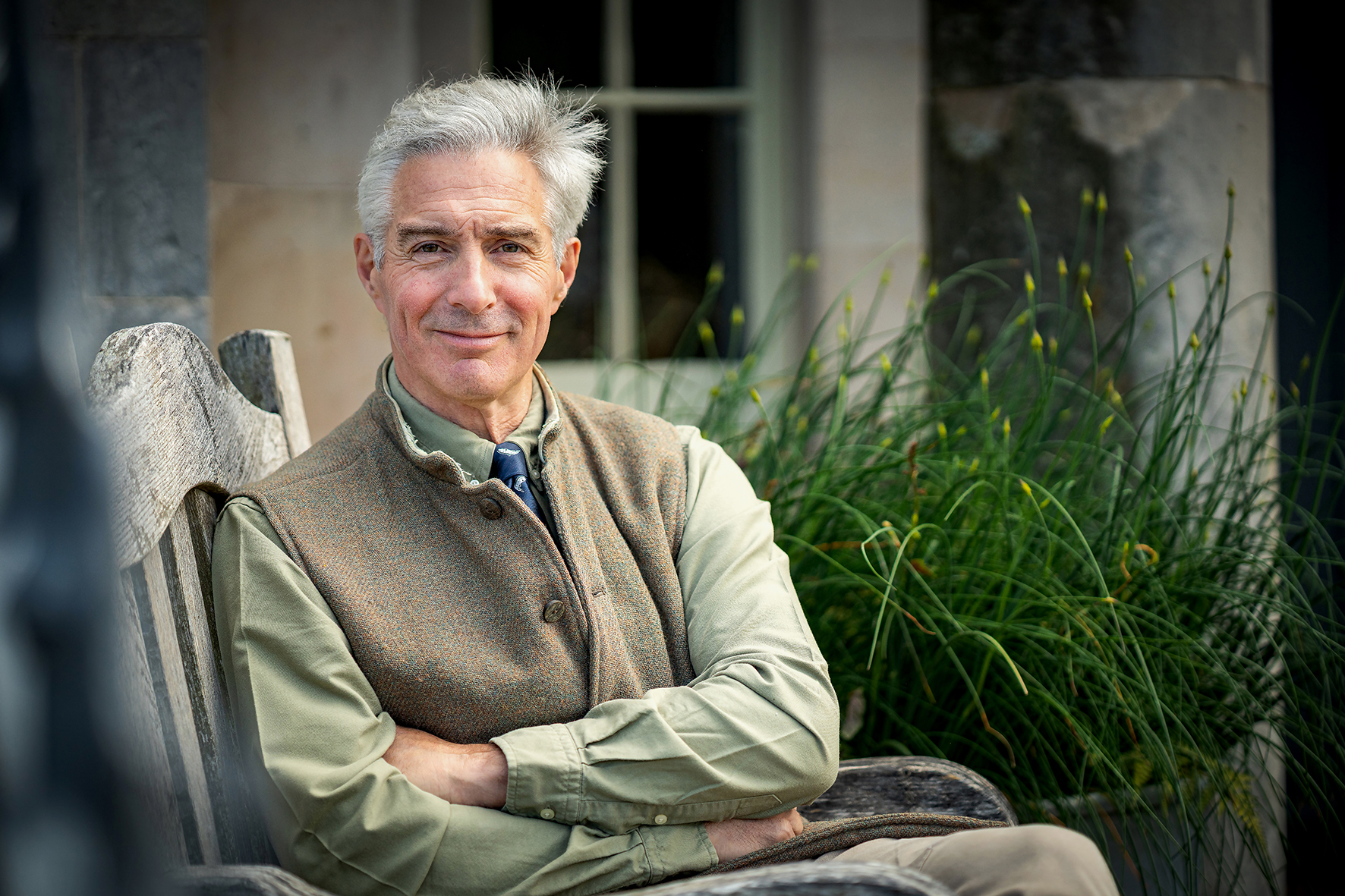 Robbie Douglas-Miller seated outdoors in shooting attire with countryside backdrop