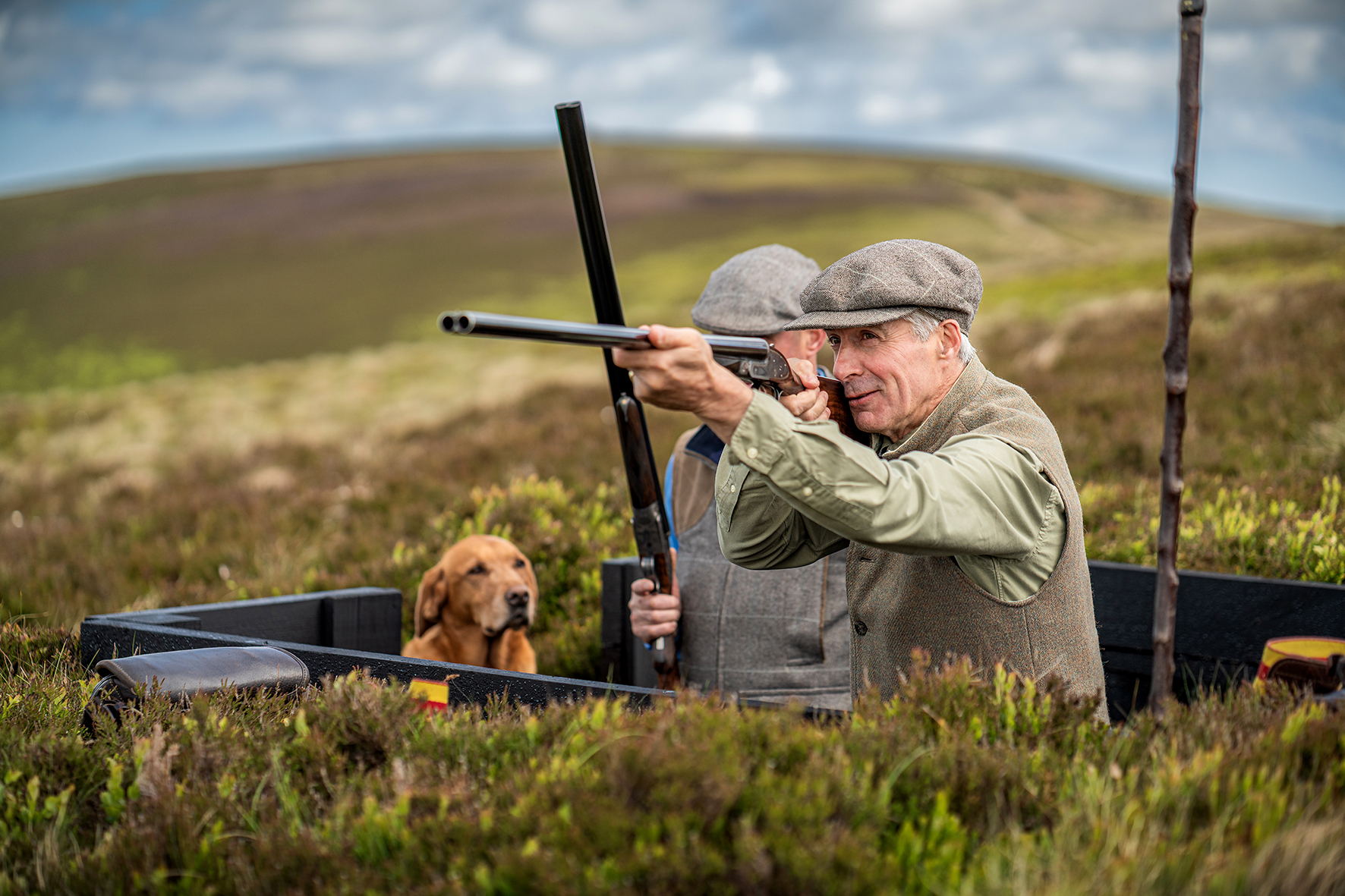 Action shot of Robbie Douglas-Miller shooting with gundog in Scottish moorland